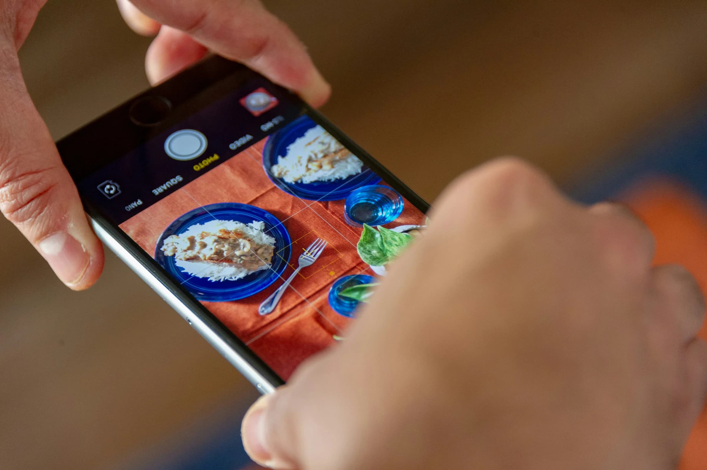 User is holding a phone, taking a photo of a meal, from above.